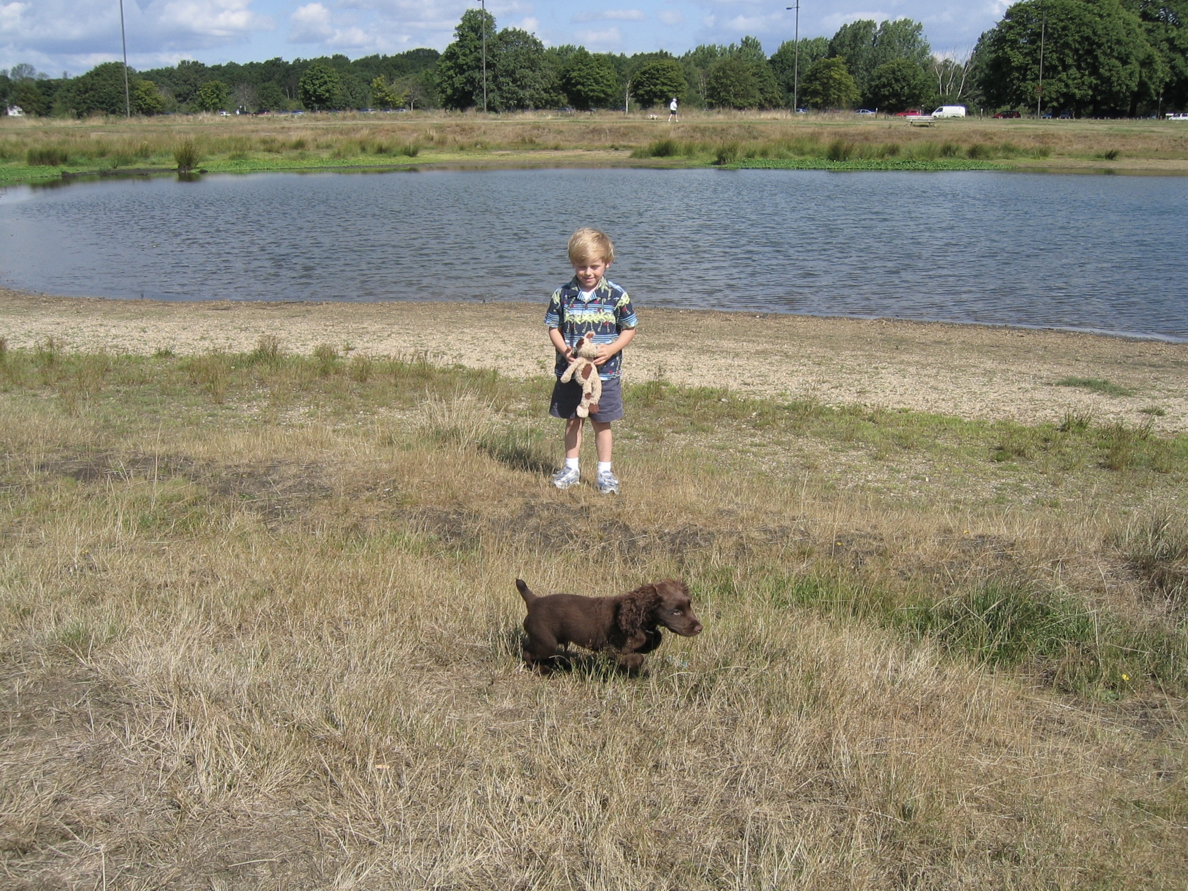A young Seb with a puppy beside a pond.