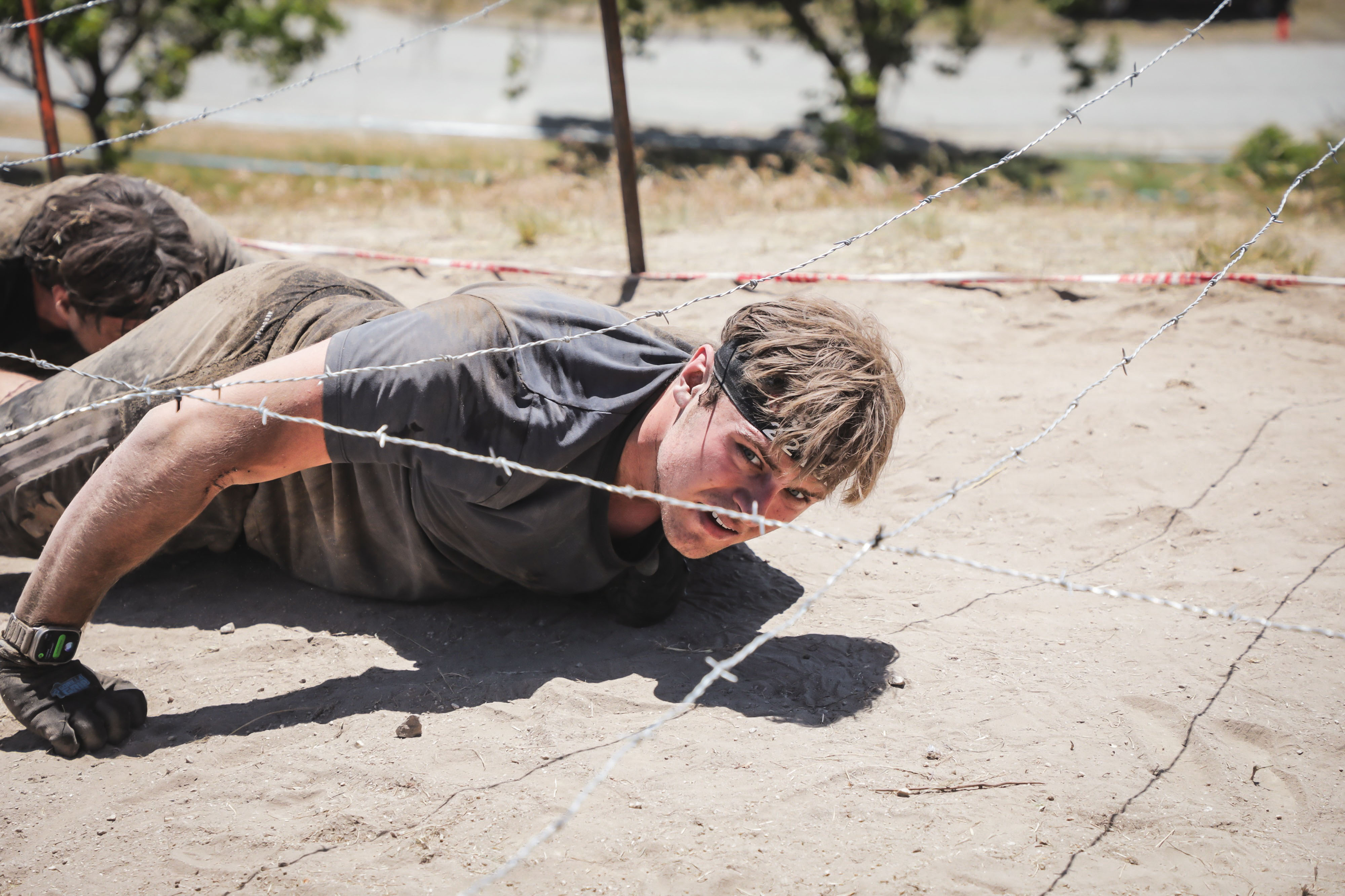 Seb crawling under barbed wire during a Spartan Race obstacle.